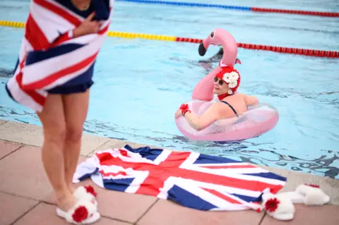 Leon Neal / Getty Images Swimmers with inflatables in an open-air lido