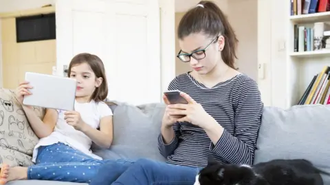 Getty Images Two children using smartphones and tablets