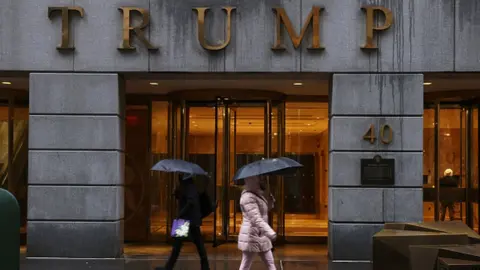 Getty Images People walk by a Trump-owned property on Wall Street