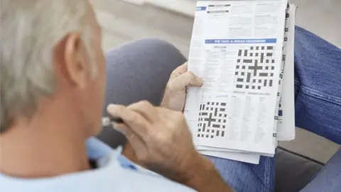 Getty Images Man doing crossword puzzles