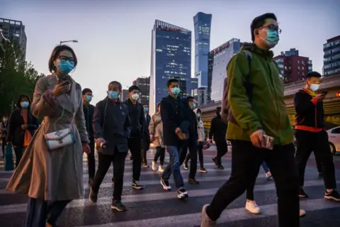 Getty Images Commuters cross an intersection during rush hour in Beijing.