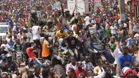AFP People celebrate in the streets with members of Guinea's armed forces after the arrest of Guinea's president, Alpha Conde, in a coup d'etat in Conakry, September 5, 2021.