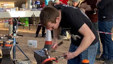 Michael Bellamy hammering a horse shoe