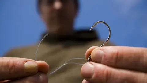 Getty Images A man tying a fishing line to a hook