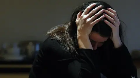 PA Media Stock picture of woman with head in hands