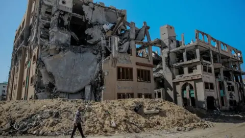 Getty Images Man walks past ruins of Gaza City's Islamic University in February 2024