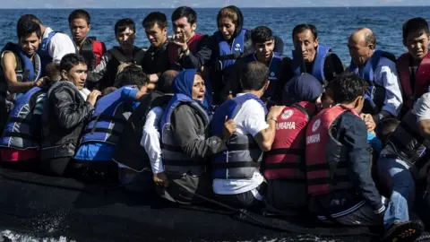 Getty Images Refugees arrive in an inflatable boat on the Greek island of Lesbos