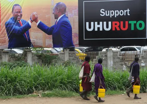 Getty Images Pedestrians walk past the campaign poster of Kenya's President Uhuru Kenyatta and Deputy-President William Ruto in Nairobi on October 23, 2017, ahead of the repeat elections. Kenyans head to the polls on October 26 for a second time this year after the Supreme Court overturned the August election victory of President Uhuru Kenyatta.