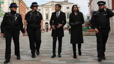 Reuters British Prime Minister Rishi Sunak visits Chelmsford, Britain March 27, 2023. Also present: Community Support Officer Sonja Viner, Police Sergeant Sophie Chesters, Home Secretary Suella Braverman and Police Sergeant Matt Collins.