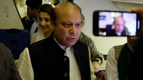 Reuters Nawaz Sharif gestures as he boards a Lahore-bound flight in Abu Dhabi. Photo: 13 July 2018