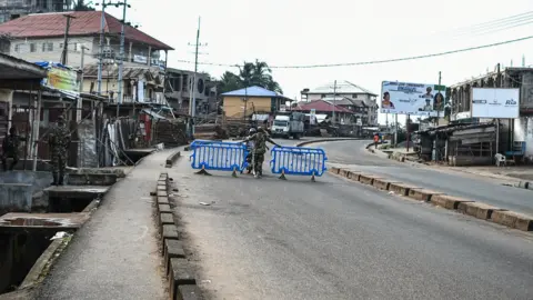 AFP A man is questioned by Sierra leonean military police at a road block in Freetown on November 26, 2023.