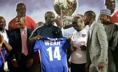 EPA President George Weah (3-L), receives his #14 jersey from Mustapher Raji (2-R), President of the Liberia Football Association(LFA), an other officials after an international friendly match between Liberia and Nigeria, to mark the final retirement of his official #14 jersey for Liberia, at the Samuel Kanyon Doe Sports Complex in Paynesville, Liberia, 11 September 2018