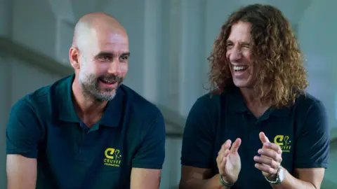 EPA Former Barcelona player Carles Puyol (right) at an event in Madrid in May 2018 talking to Manchester City coach Pep Guardiola (left)