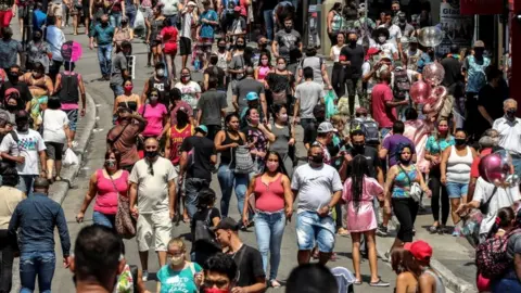 EPA Dozens of people walk along a shopping street in downtown São Paulo, Brazil, 7 October 2020.