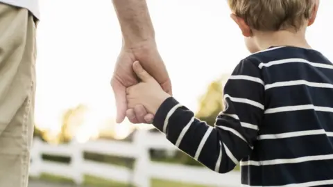 Getty Images Father holding child's hand