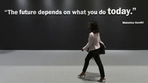 AFP A participant walks past a wall showing a quote by Indian pacifist Mahatma Gandhi at the UN Climate Change Conference