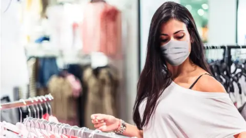 Huw Evans picture agency woman in clothes shop with mask