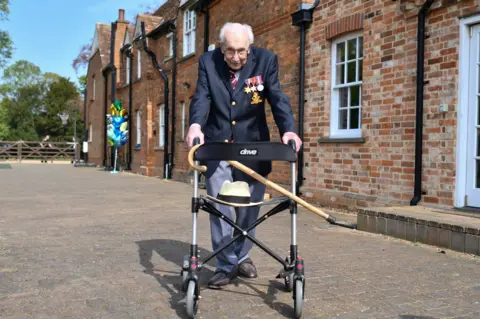 Getty Images Captain Sir Tom Moore walks alongside his house whilst holding on to a walking frame