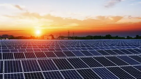 Getty Images The Sun rises over rows over solar panels