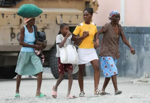 Reuters Residents carry belongings as they leave their homes due to gang violence, in the Pernier section of Port-au-Prince, Haiti January 30, 2024. REUTERS