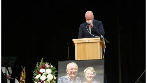 Supplied Simon Patterson speaks at a memorial service for his parents