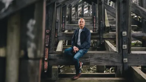 BBC Andrew Smith sits on the timber decking at Dunston Staiths