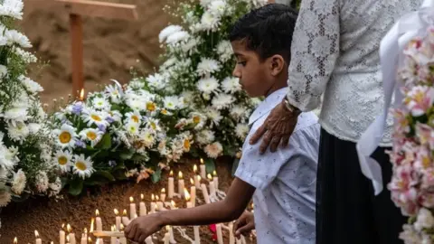 Getty Images A young boy lights a candle at a grave after a funeral for a person killed in the Easter Sunday attack on St Sebastian"s Church, on April 25, 2019 in Negombo, Sri Lanka.