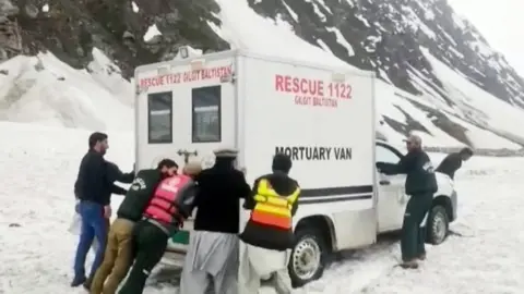 Men pushing a mortuary van in the snow