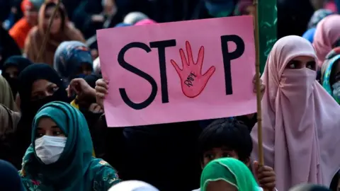 Getty Images A woman holds a placard reading "Stop" during a protest against an alleged gang rape of a woman in Pakistan, 2020