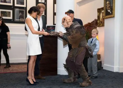 Getty Images Meghan being given a gift by an orc soldier