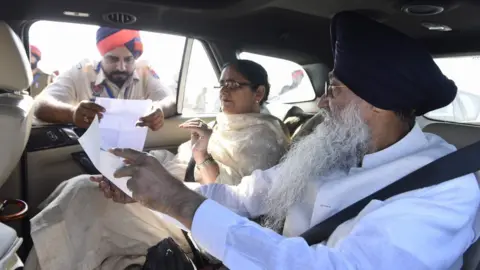 AFP Indian Sikhs show papers to Indian border guards before crossing to Pakistan