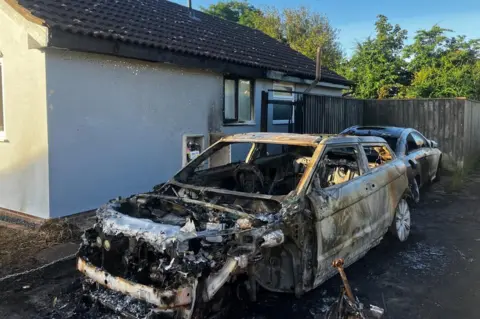 Matt Marvel/BBC Two burnt out cars next to a bungalow in Trimley St Martin