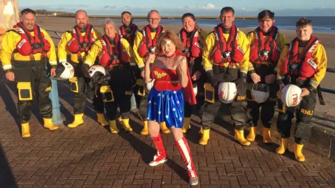 Canon Alan Hughes One dipper dressed as Wonder Woman with RNLI volunteers