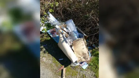 Wiltshire Council Rubbish dumped on the ground near a lot of twigs - mostly plastic and cardboard