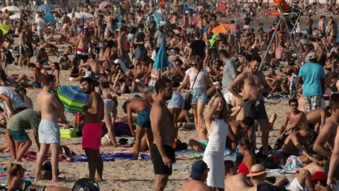EPA Beachgoers bask in the sun as they enjoy a warm afternoon in Barcelona on 17 July