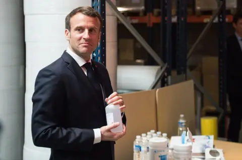 Getty Images French president Emmanuel Macron with some bottles of hand sanitiser