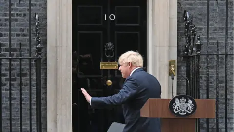 BBC Mr Johnson waves as he turns towards the door at 10 Downing Street