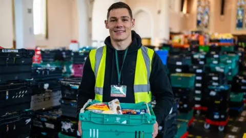 Bournemouth Foodbank Chris Billam-Smith wearing a hi-vis vest and sorting food at Bournemouth Foodbank warehouse