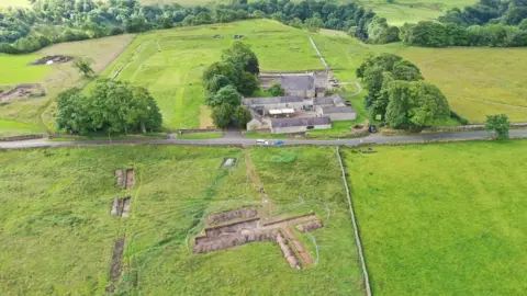 Historic England Aerial view showing multiple exposed digs in fields around the Roman fort