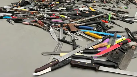 Becki Thomas / BBC Pile of knives on floor