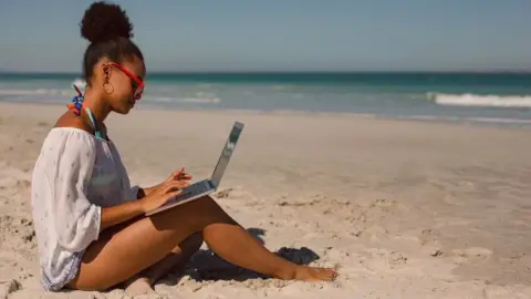 Getty Images A woman on the beach with a laptop