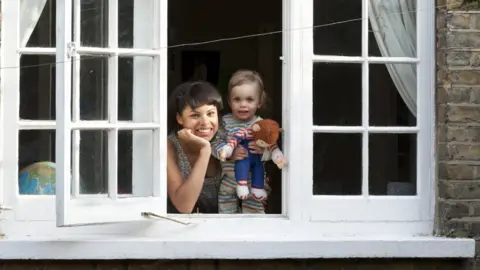 Getty Images Woman and toddler looking out of an open window