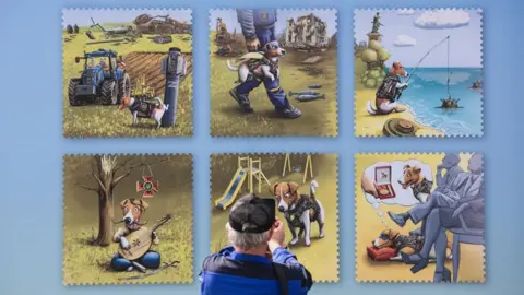 DSNS Man stands in front of billboard showing six stamps with Patron the dog on