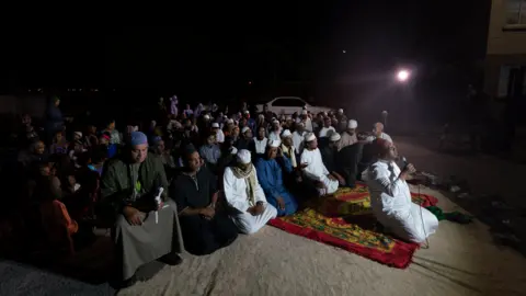 BBC/Shiraaz Mohamed People kneeling during a dhikr session in Manenberg, Cape Town - South Africa