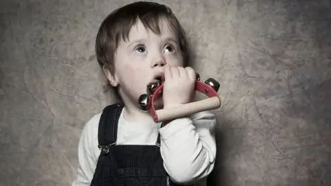 Debbie Todd A young boy holds a musical rattle up to his mouth