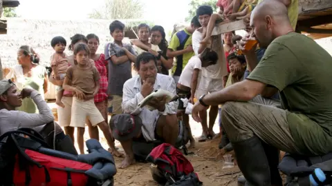 Keith Ducatel Ed Stafford stops for a drink watched by villagers