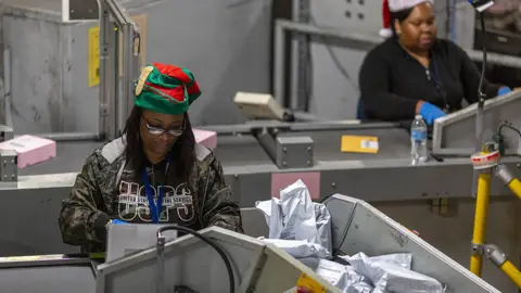 Getty Images A US postal worker sorting holiday season parcels