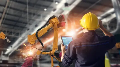 WRC-19 A man operates robots in a factory using a computer