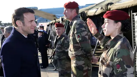 Getty Images French President Emmanuel Macron greets soldiers as he visits the Mont-de-Marsan air base, southwestern France, to deliver his New Year address to the French Army on January 20, 2023