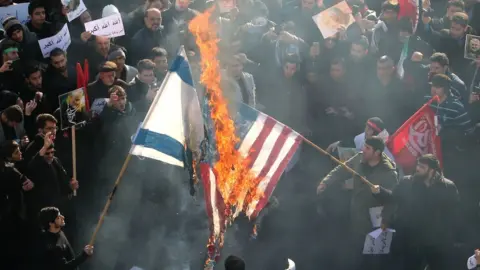 AFP Iranians set a US and an Israeli flag on fire during a funeral procession in Tehran, 6 January 2020